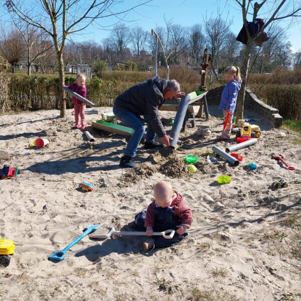 Opa en zijn kleinkinderen aan het spelen in de zandbak